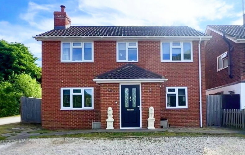 A two-story brick house with a dark blue front door.