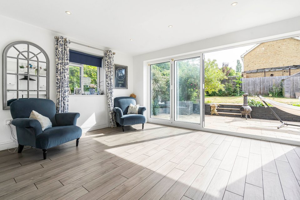 Interior view of a home's sunlit living room with patio doors opening to a garden.