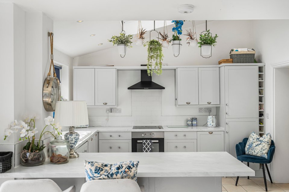 Photo of a bright kitchen with white cabinets and a marble countertop.