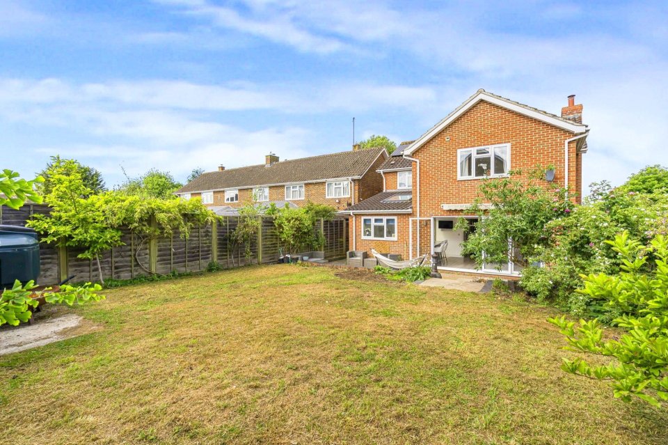 Photo of a house's backyard with a brown lawn and brick house.