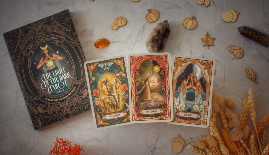 Tarot cards from *The Light in the Dark Tarot & Oracle* deck displayed with the guidebook.