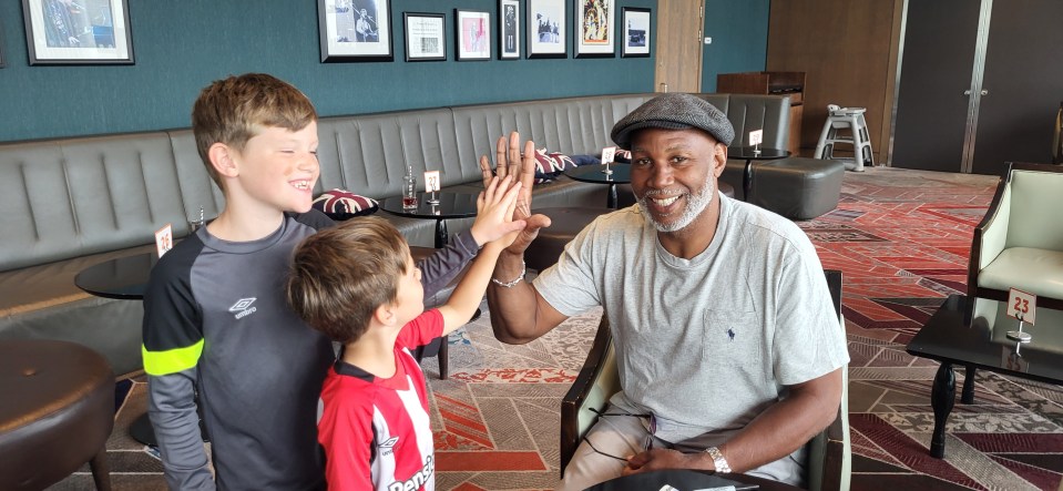 Lennox Lewis giving high fives to two boys.