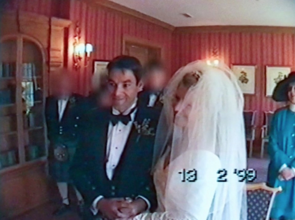 Video still image of a wedding; the groom is smiling.