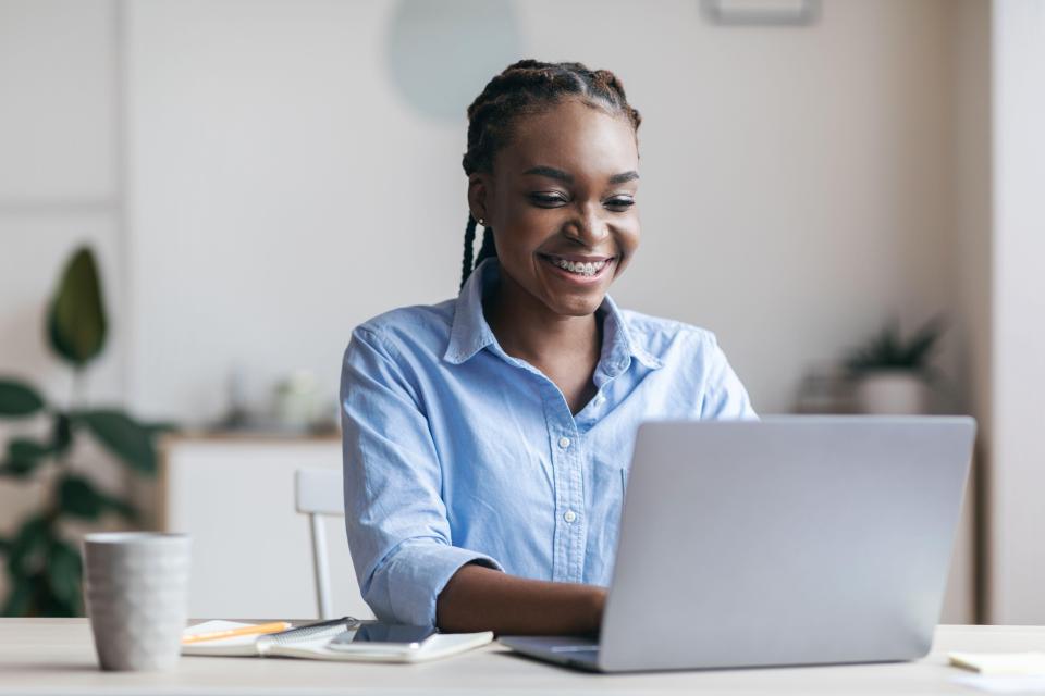 Smiling Black woman working on laptop.