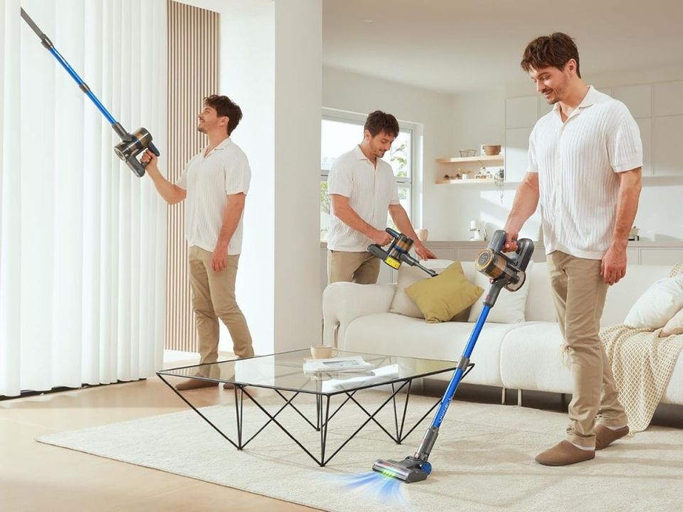 Three men using a cordless vacuum cleaner in a living room.
