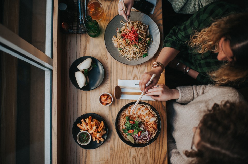 Overhead view of two people using chopsticks to eat Asian food at Wagamama.