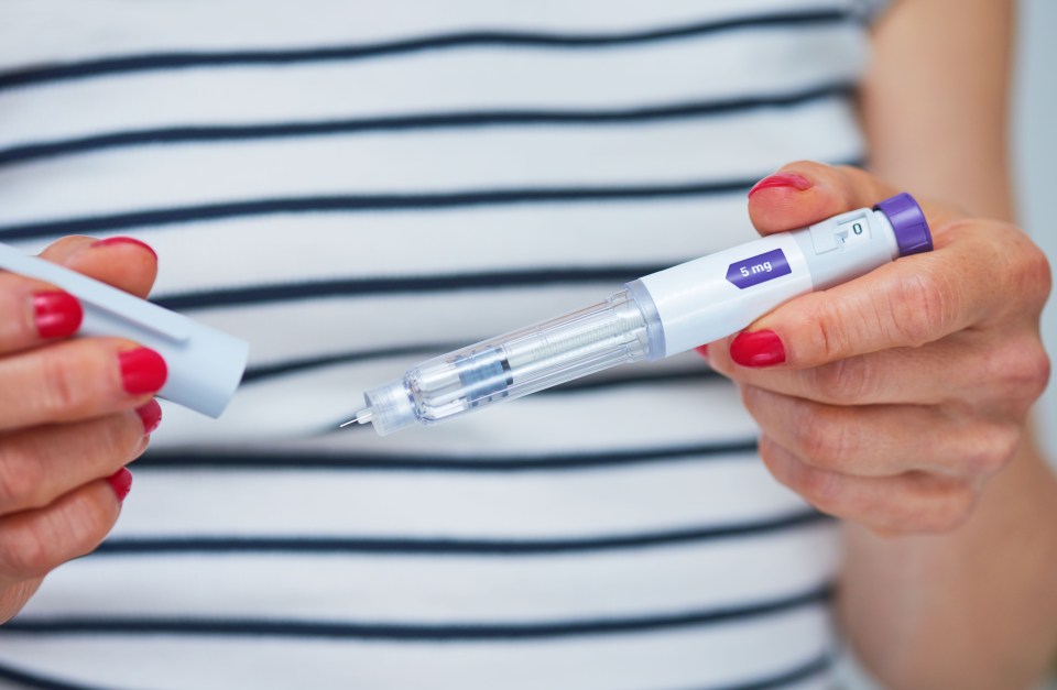 A woman holds a 5 mg injection pen.