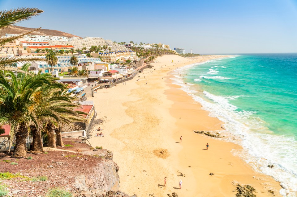 Sandy beach in Morro Jable, Fuerteventura with turquoise water and hotels.