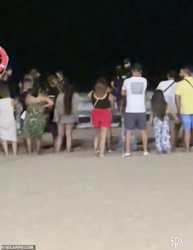 A British tourist has drowned in Benidorm after jumping into the sea for a late evening swim. Pictured: Police attend the accident scene last night as a crowd gathers