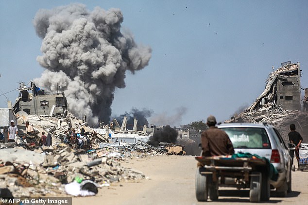 People watch as smoke billows following an Israeli strike in Jabalia, in the northern Gaza Strip on May 25, 2025