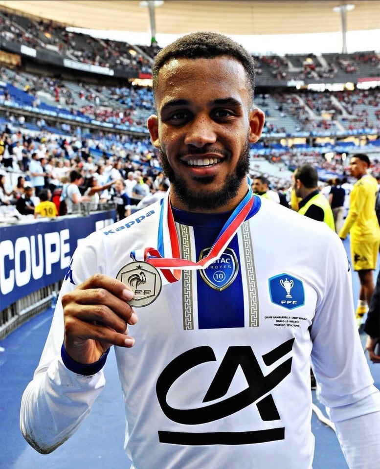 Man in soccer jersey holding a medal.