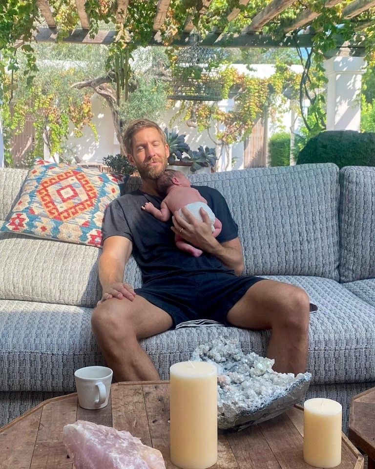Man holding a baby on a couch outdoors.