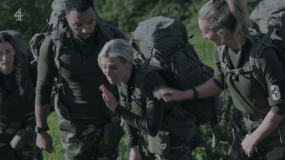 Soldiers carrying heavy backpacks; one woman appears to be struggling.