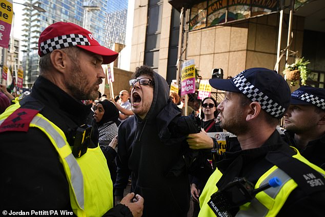 A protester who was asked to remove his face mask shouts at a police officer whilst taking part in the Stand Up to Racism rally outside the Britannia International Hotel on Friday