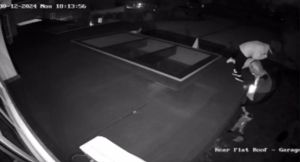 Nighttime security camera footage of burglars stealing jewelry.
