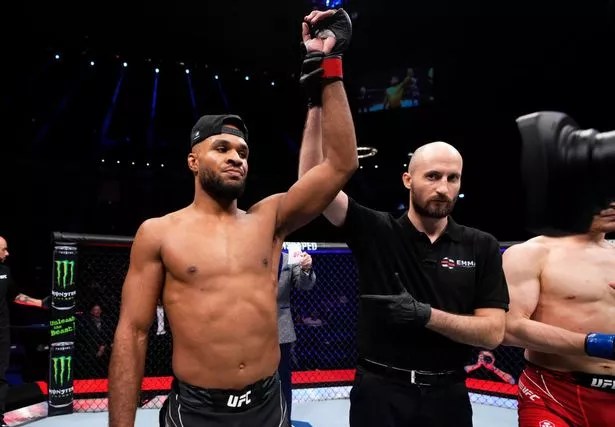 A UFC fighter raises his arm in victory.