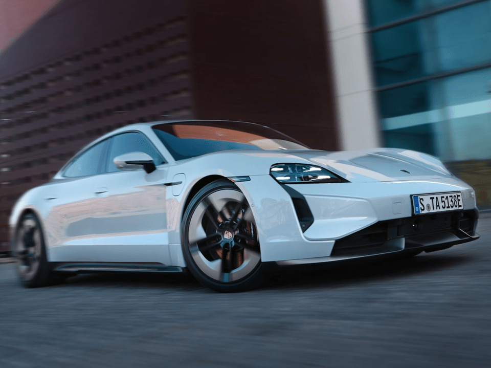 White Porsche Taycan driving down a city street.