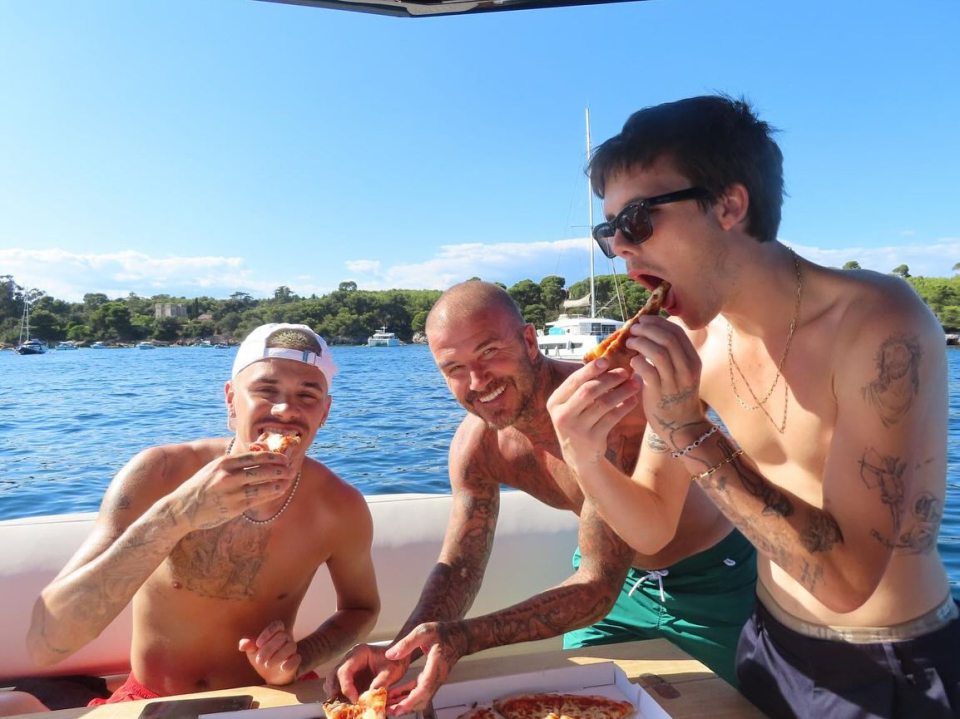 Three men eating pizza on a boat.