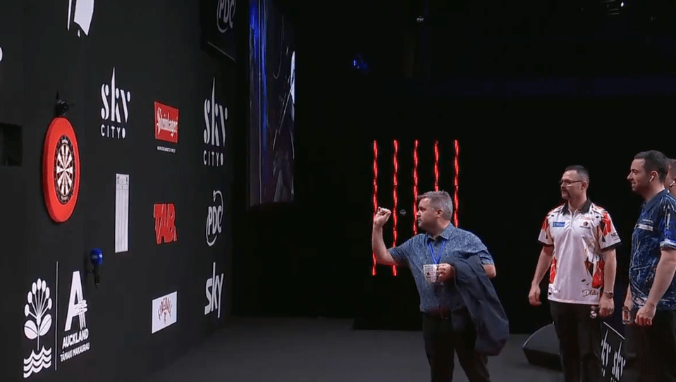 Darts player throwing a dart at a dartboard.