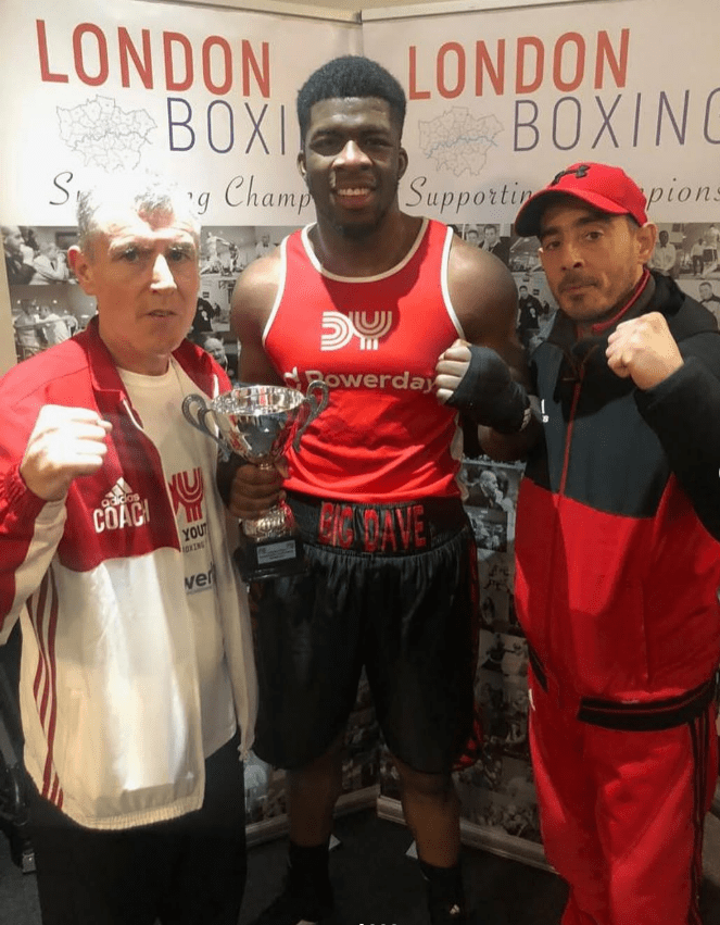 Boxer with two coaches holding a trophy.