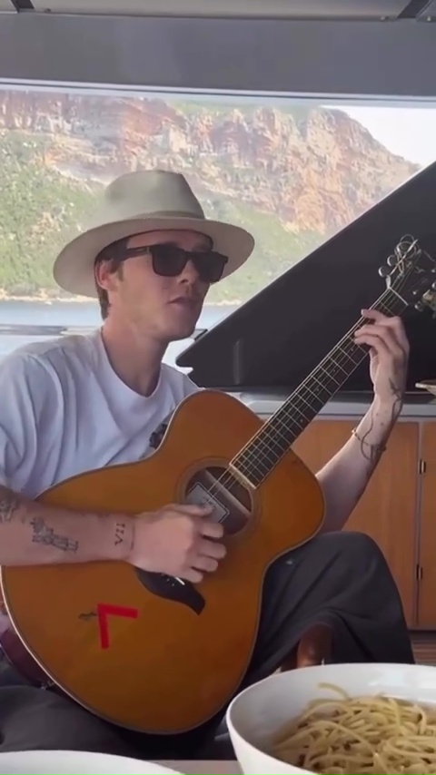 Cruz Beckham playing guitar on a yacht.