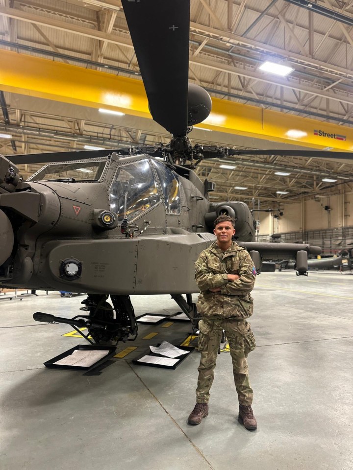 Soldier standing in front of a military helicopter.