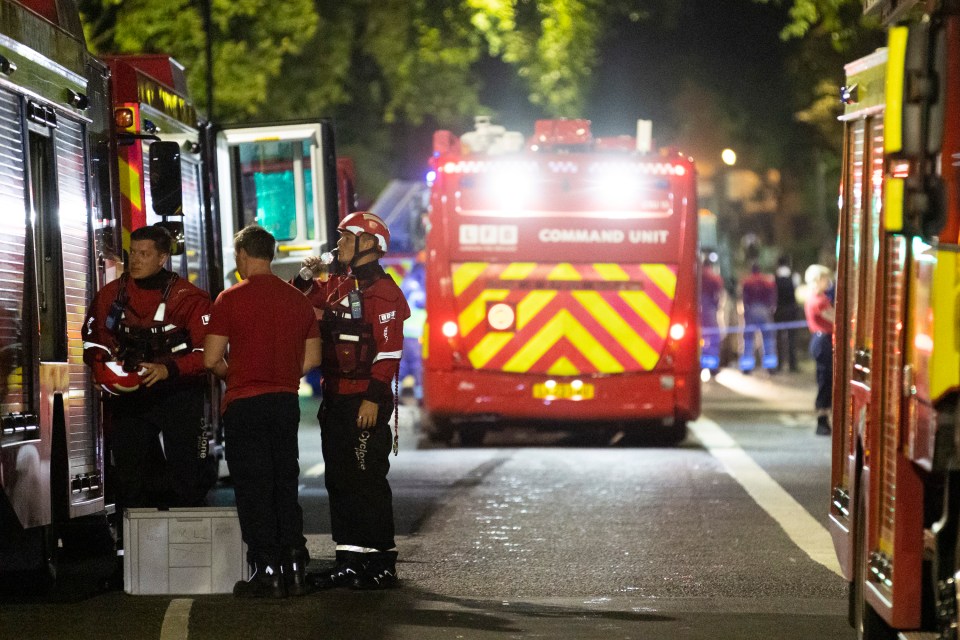 Firefighters taking a break near fire engines at night.