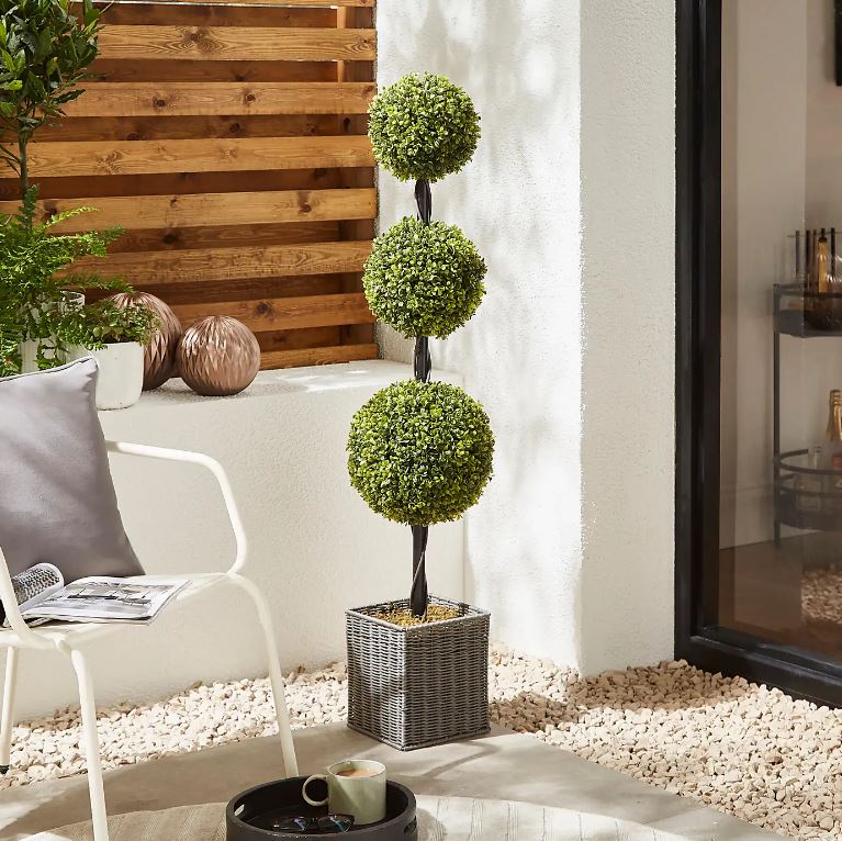 Artificial boxwood ball tree in a woven plant pot.
