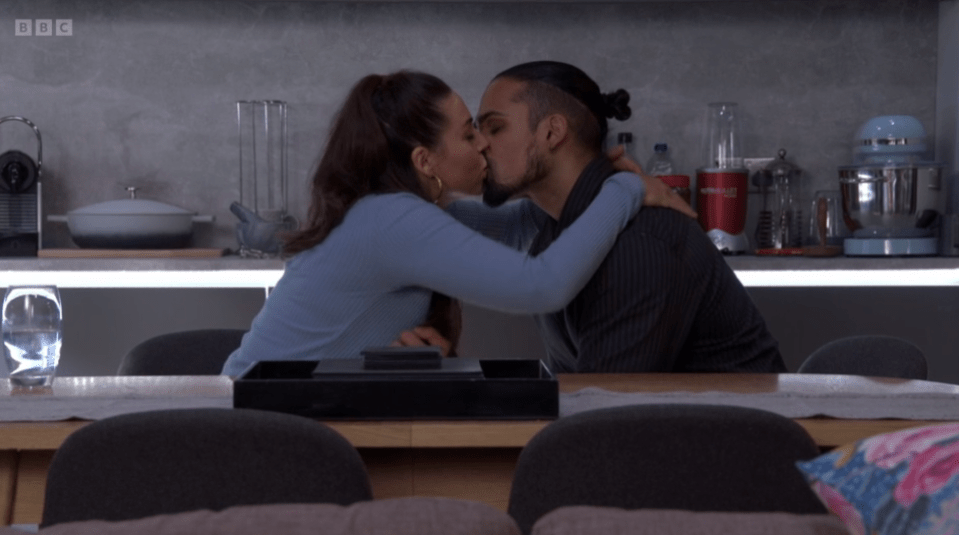 Screenshot of a couple kissing in a kitchen.