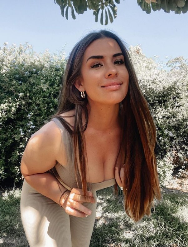Woman in beige outfit posing outdoors.