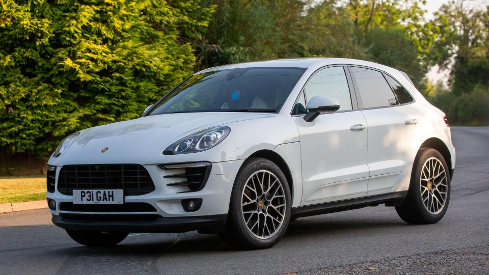White Porsche Macan driving on a road.
