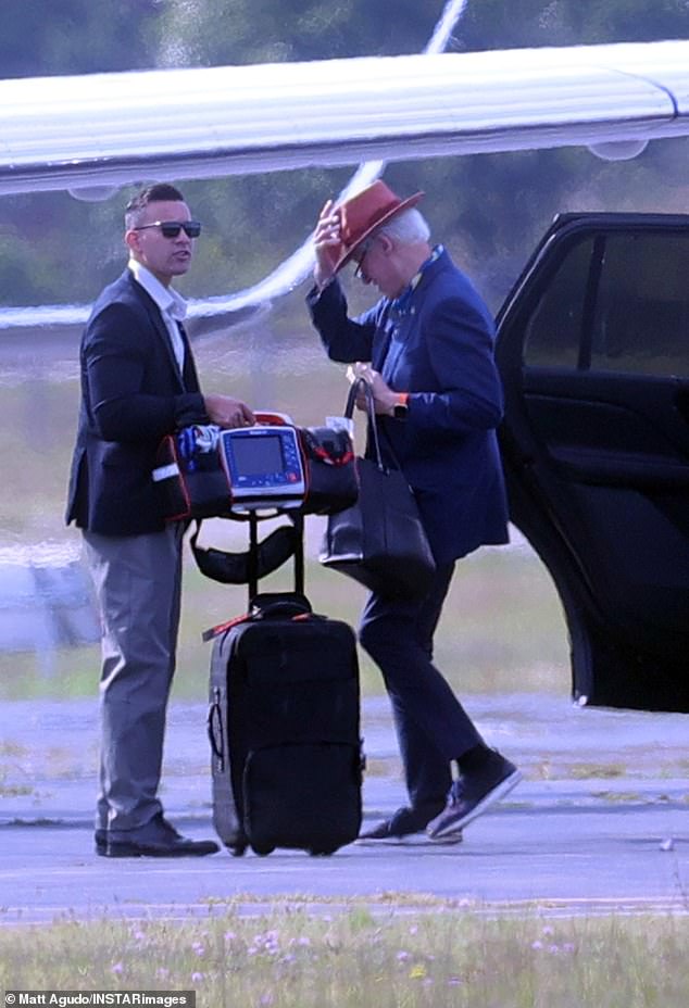 The former president wore a blue jacket and tan hat as he exited a vehicle and was accompanied by members of his security carrying a defibrillator