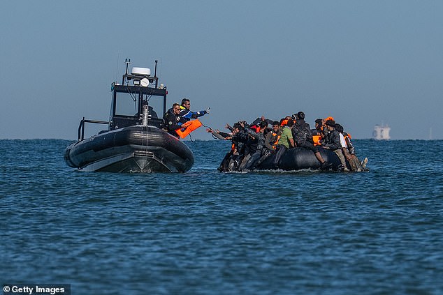 A French police vessel passes lifejackets to people on a dinghy as they cross the English Channel
