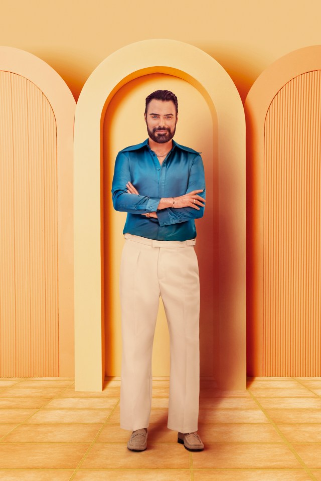 Rylan Clark, arms crossed, standing in a peach-colored archway.