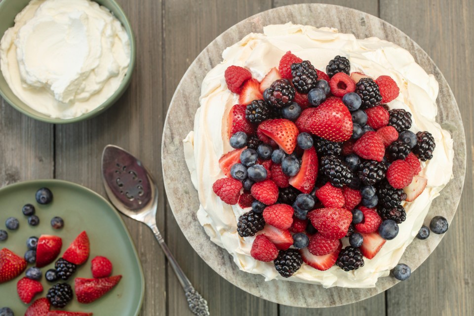 Pavlova meringue cake topped with strawberries, raspberries, blackberries, and blueberries.