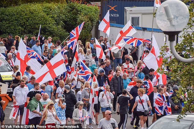 Crowds of anti-migrant demonstrators holding English flags and Union Jacks gather outside the Crowne Plaza hotel in West Drayton