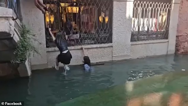This is the moment soaking tourists are dragged out of a canal in Venice after tipping over their boat while posing for selfies