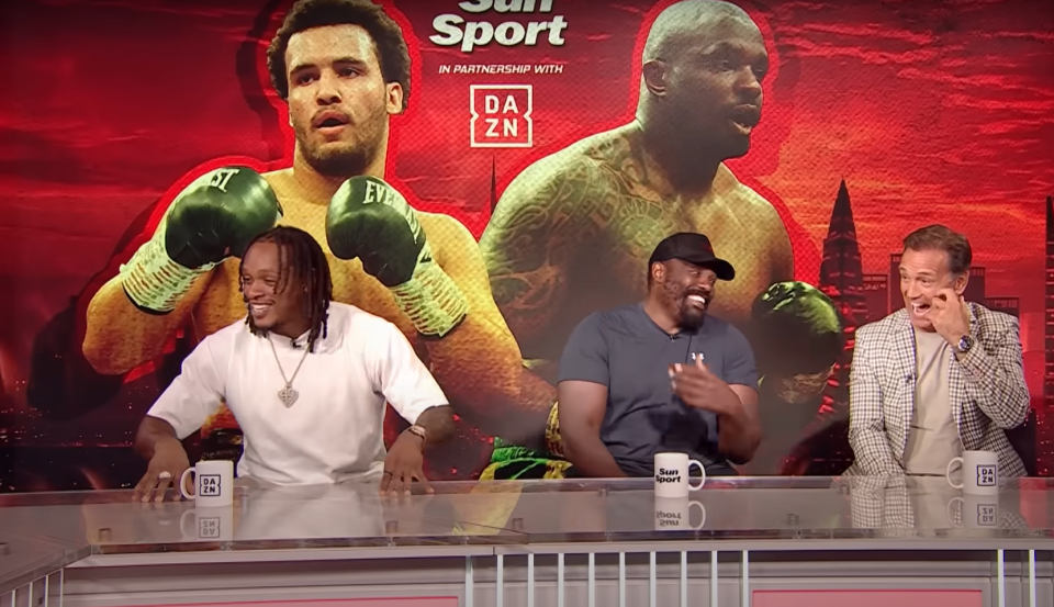 Three men on a sports show panel, behind them is a boxing match graphic.