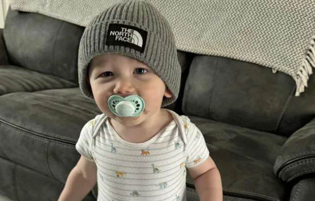 Baby wearing a The North Face beanie and pacifier.