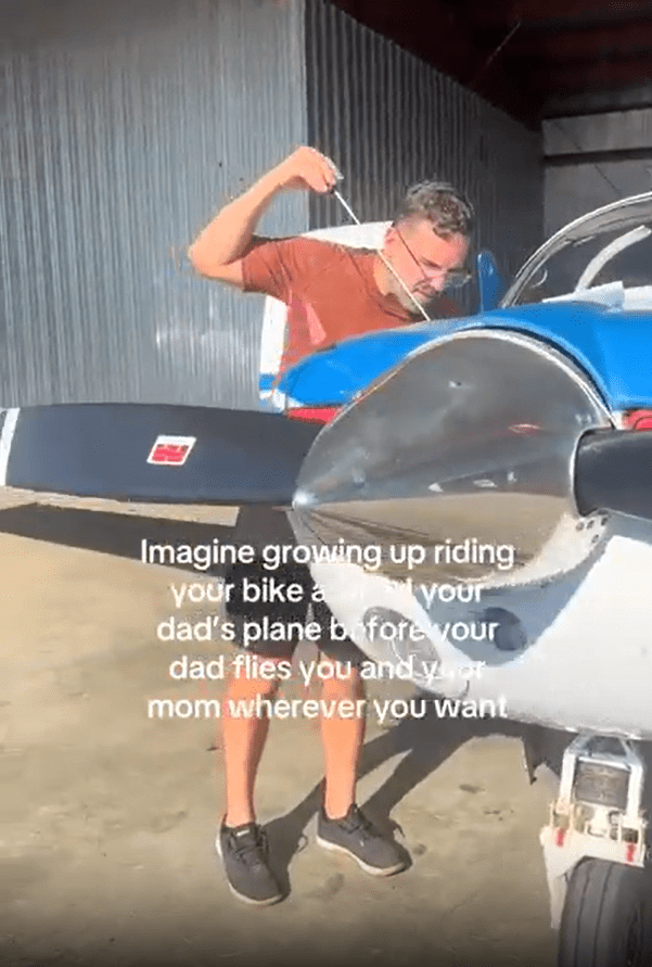 Man checking the oil of a small airplane.