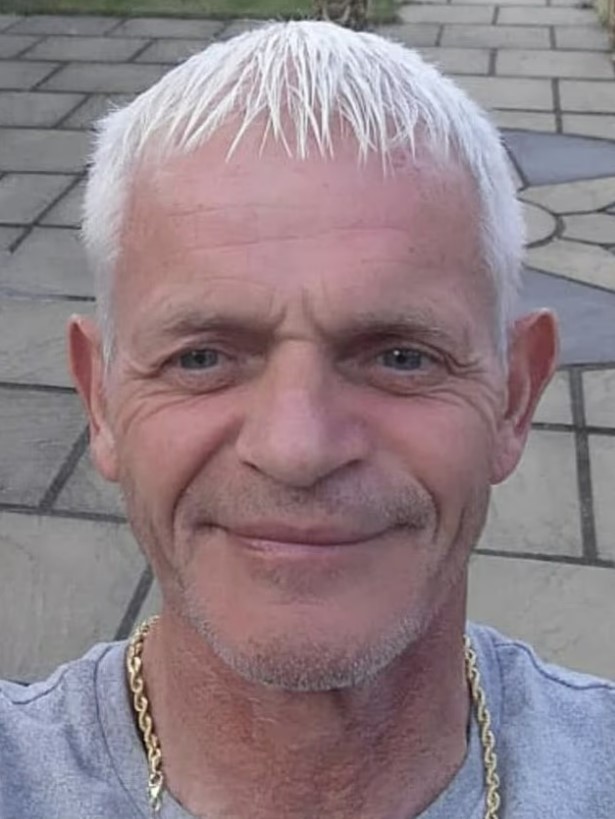Portrait of a man with short, gray hair and a gold chain.