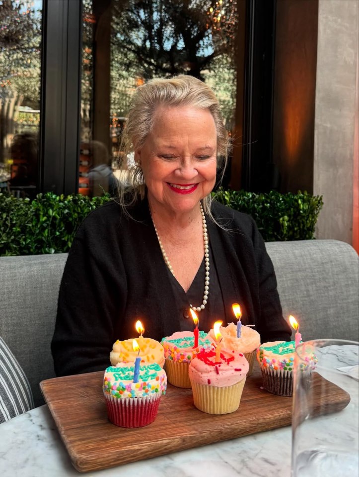 Woman looking at birthday cupcakes with lit candles.
