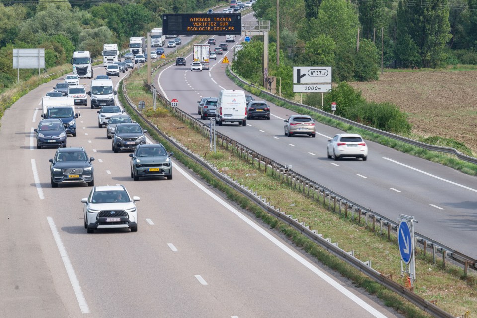 Highway traffic with a billboard warning about Takata airbags.
