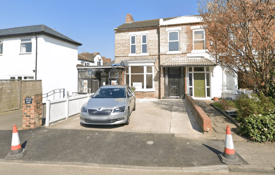 Photo of a brick house with a silver car parked in front.