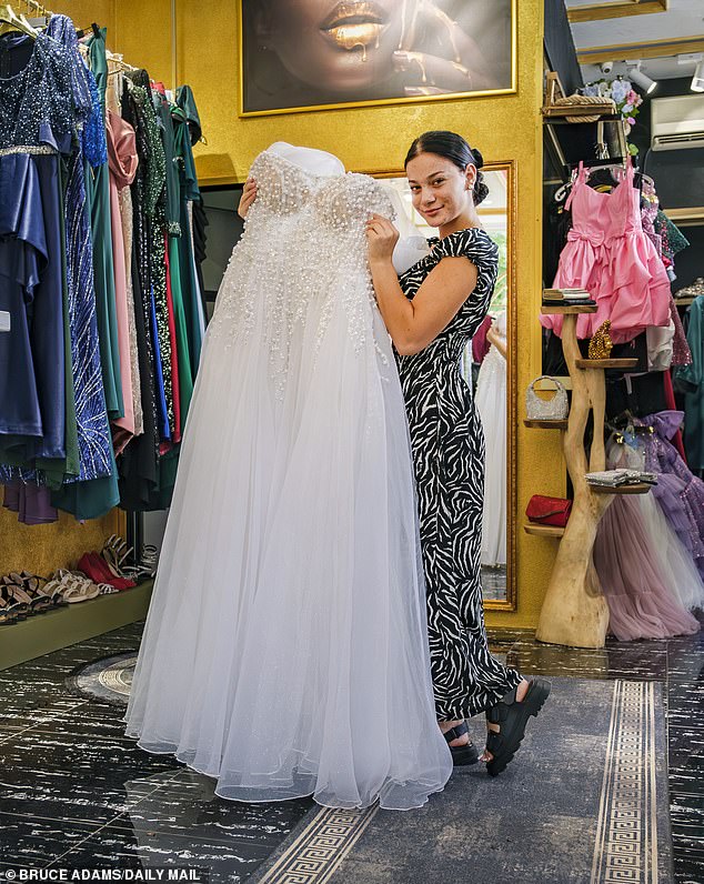 Sales assistant Doriana Laci, 19, at a bridal shop in has showing off the wedding dresses available to Albanian women who marry before their husbands make the illegal journey to the UK