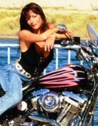 Woman sitting on a motorcycle by the water.