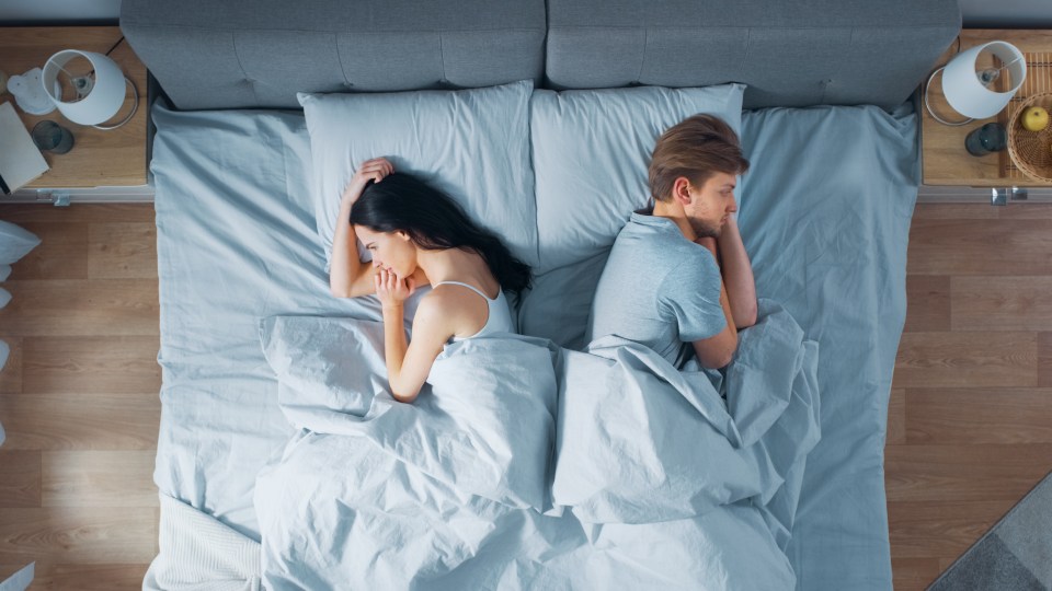 a man and a woman laying back to back on a bed