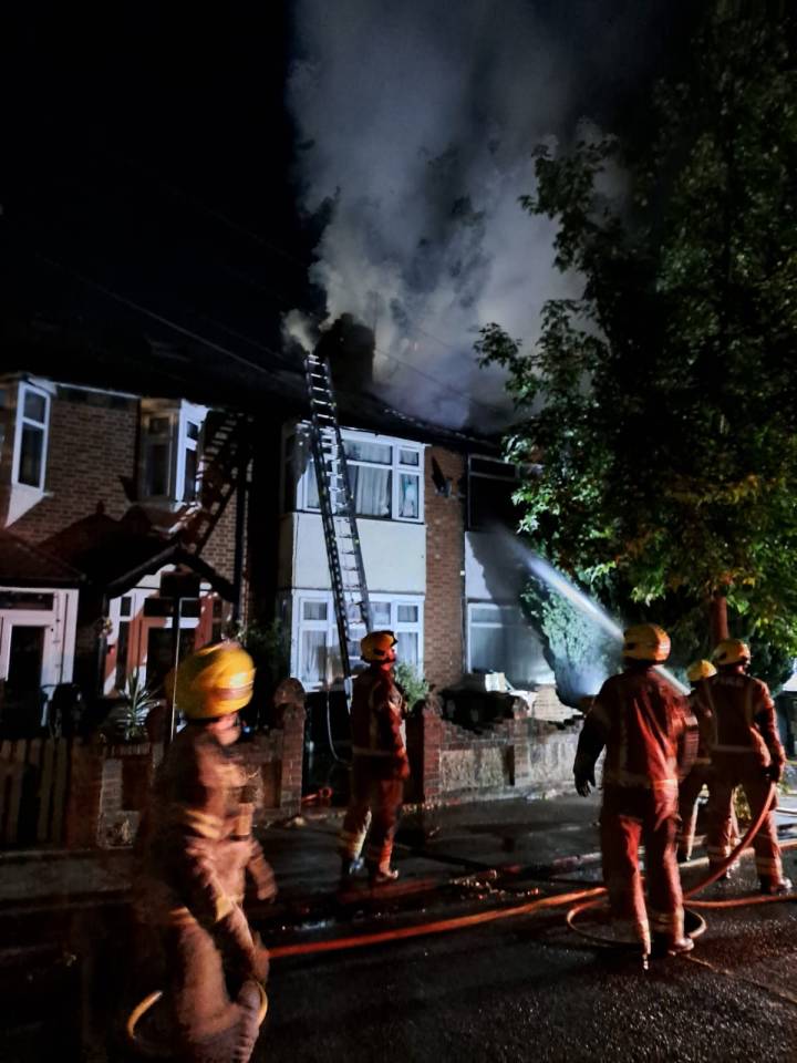 Firefighters extinguishing a house fire at night.