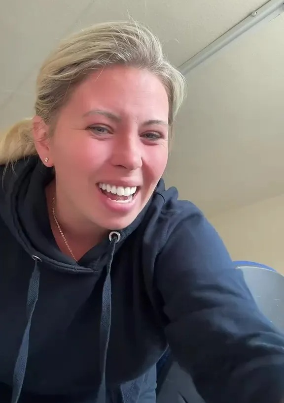 Woman in a black hoodie smiling.