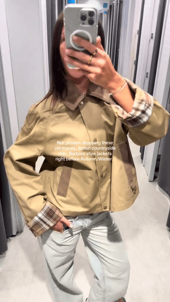 Person modeling a tan Barbour-style jacket in a Primark changing room.